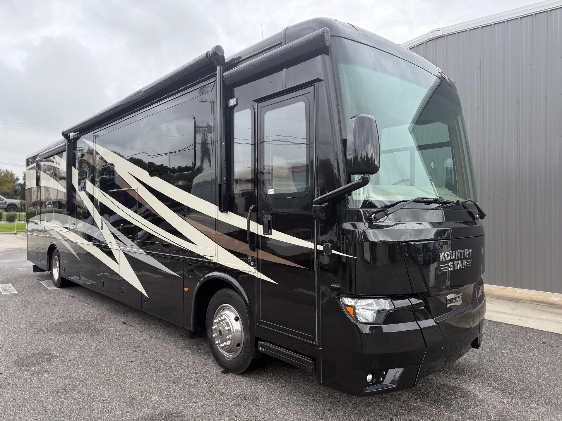 2020 Newmar Kountry Star 4037 — The front and side exterior shell of a Kountry Star motorhome, including body, windshield, awning, and wheel