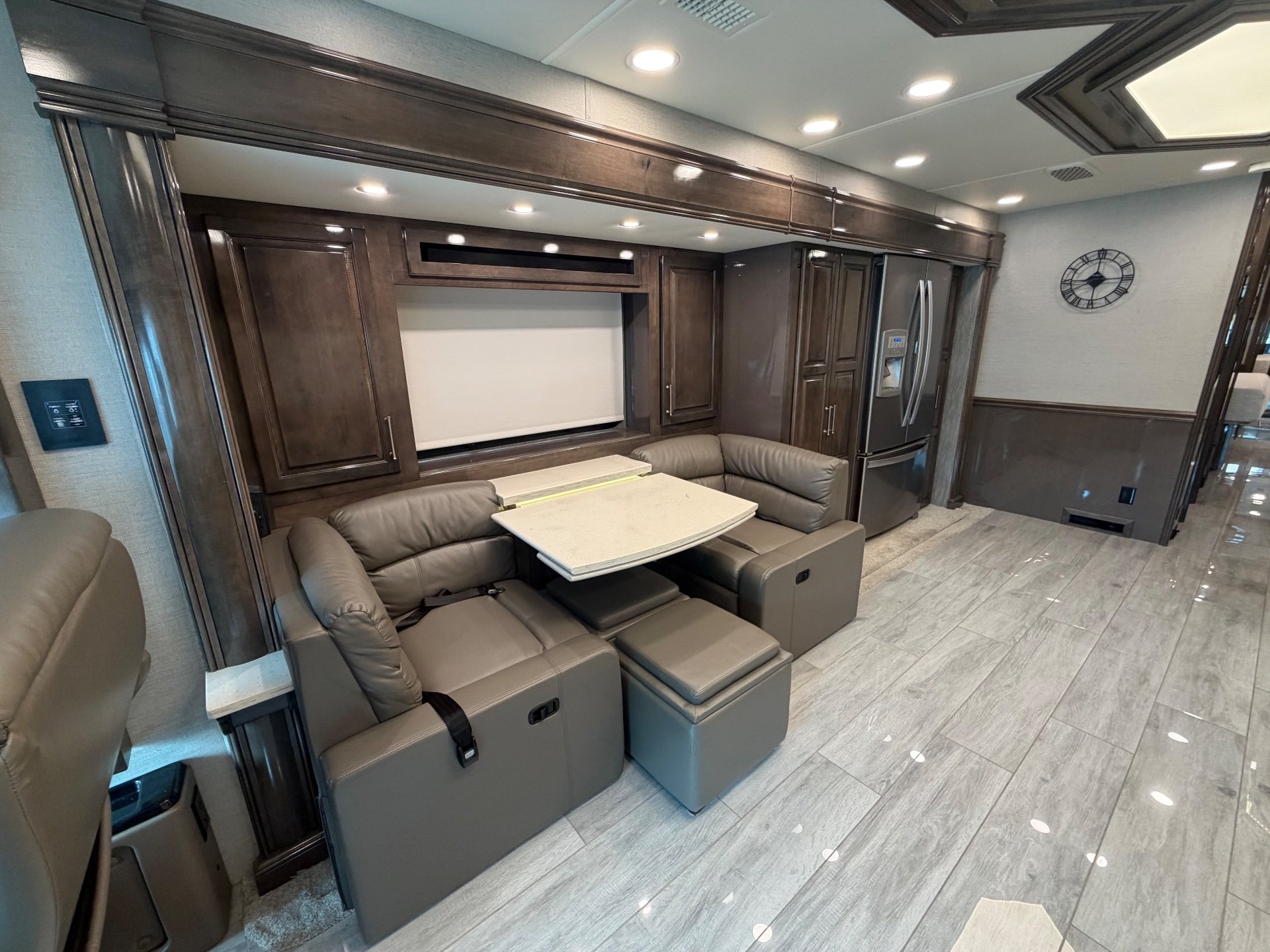 2020 Entegra Coach Aspire 44R — Motorhome dinette with opposing leather benches, table, refrigerator, kitchen cabinetry, and open lounge space