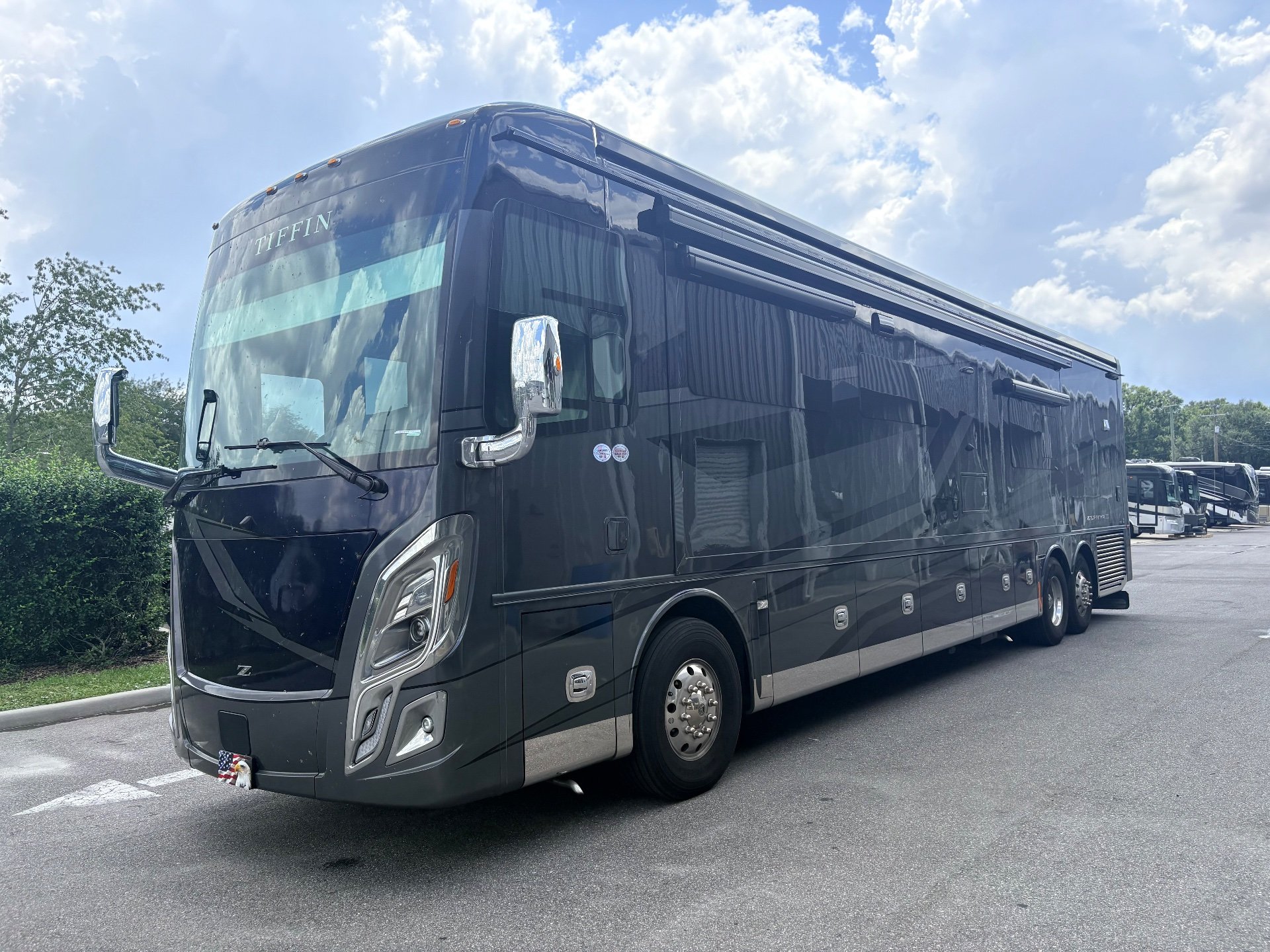 2025 Tiffin Zephyr 45 PZ — The motorhome's front and passenger-side exterior, including wheels, awnings, and body panels