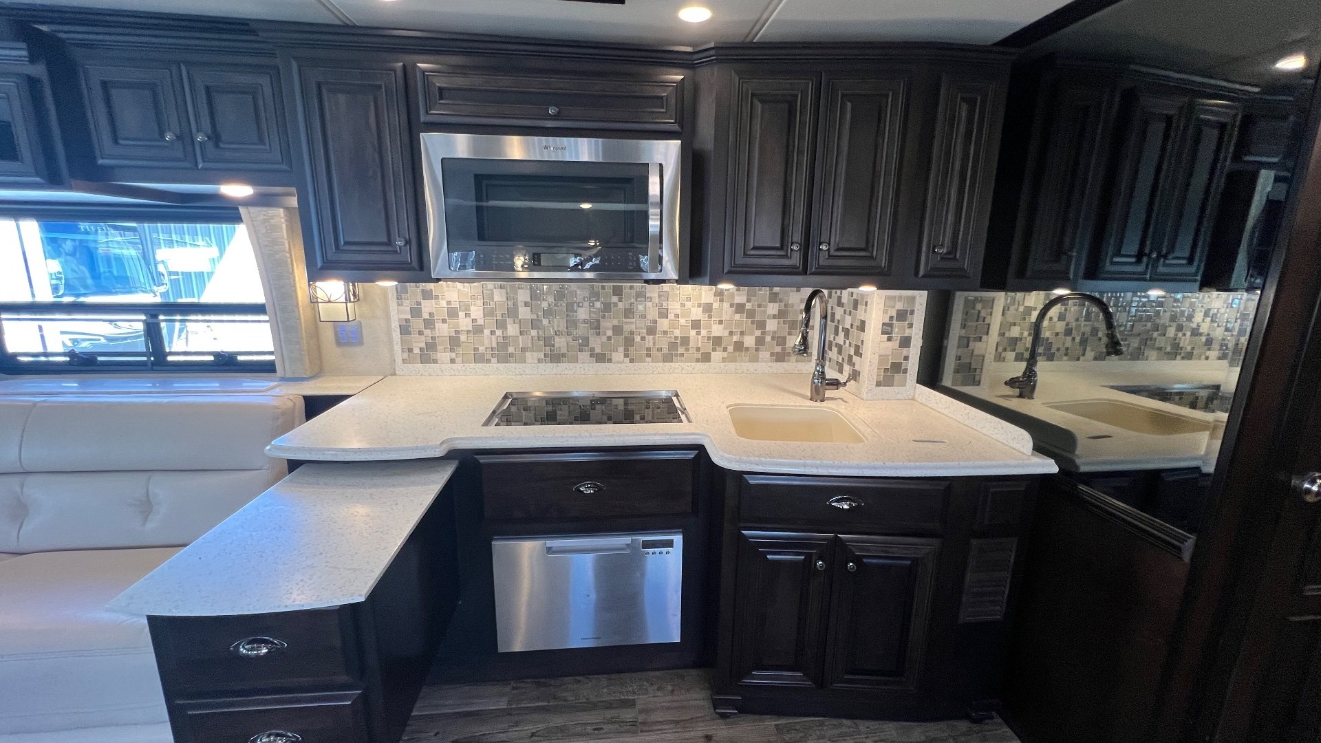 2018 Newmar Dutch Star 4369 — Kitchen with island extension, sink, cooktop, microwave, dishwasher, backsplash, and adjacent sofa
