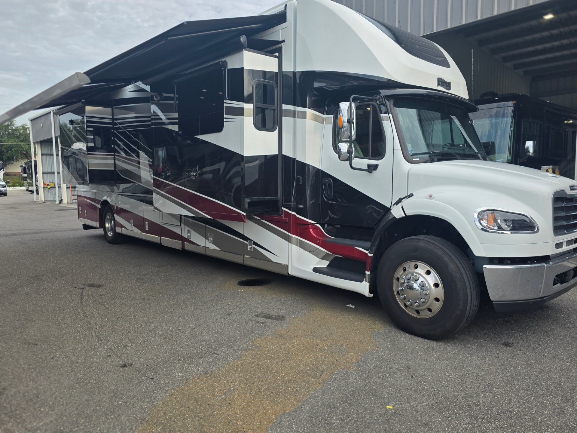 2024 Newmar Super Star 4061 — The complete exterior front and side of the motorhome with awning and slide-outs