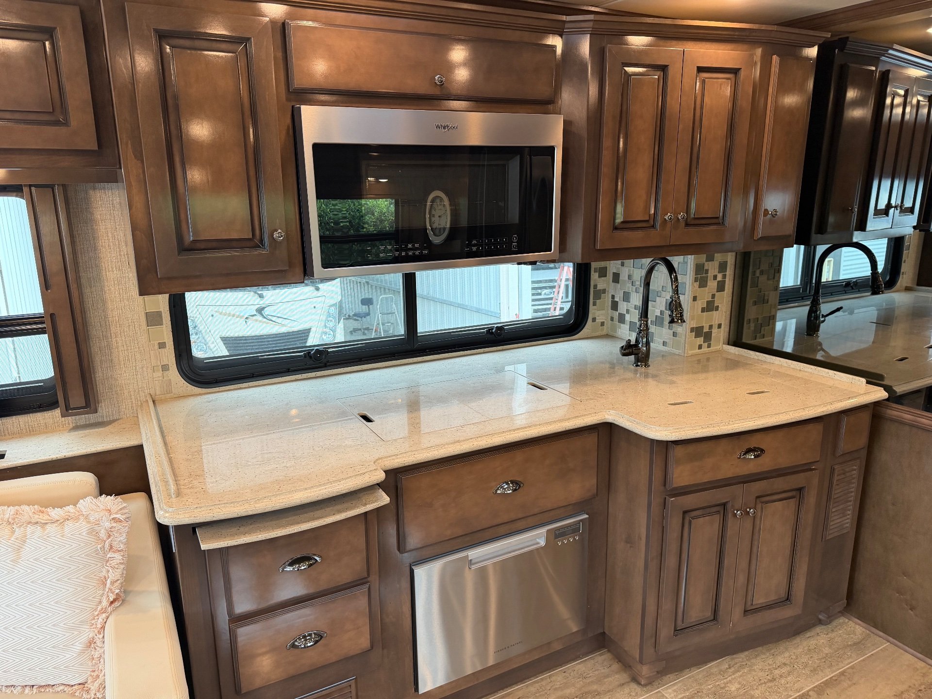 2021 Newmar Dutch Star 4369 — Motorhome kitchen counter with sink, faucet, microwave, dishwasher, drawers, backsplash, and overhead cabinets