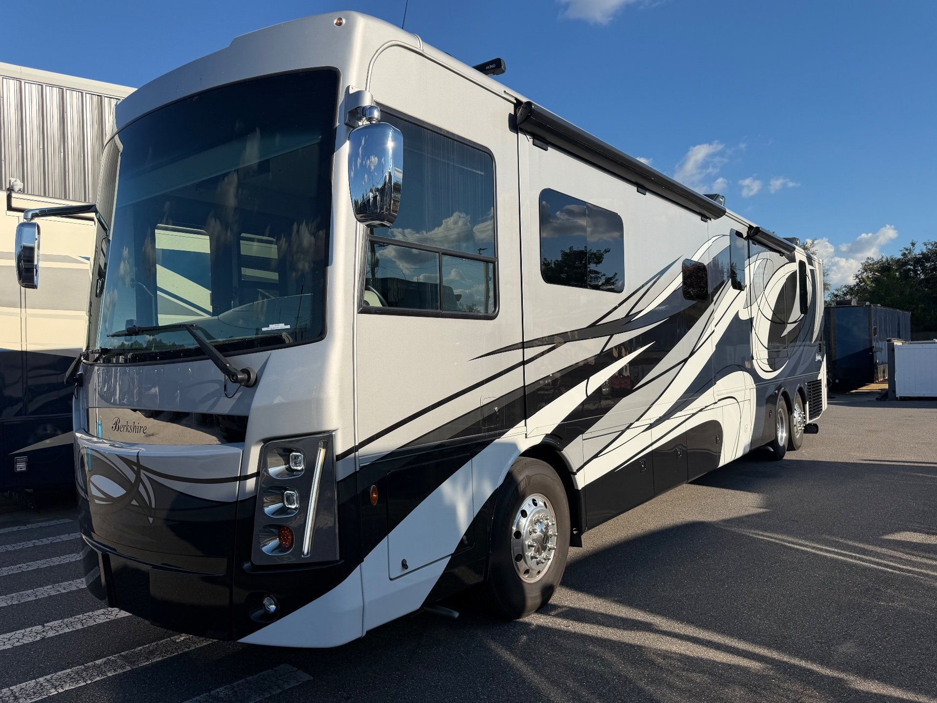 2023 Forest River Berkshire XLT 45E — The motorhome's front and side exterior, with exterior windows, awning, mirrors, body graphics, and wheel