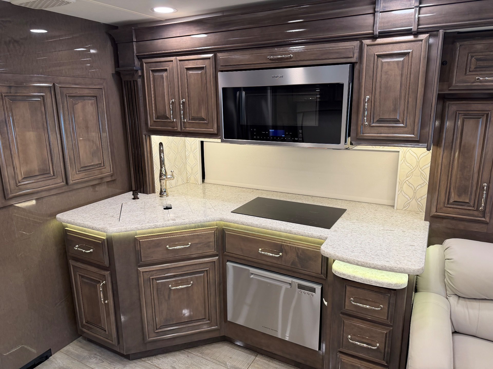 2021 Entegra Coach Cornerstone 45F — Motorhome kitchen with corner counter, sink, induction cooktop, microwave, dishwasher, drawers, and overhead cabinets
