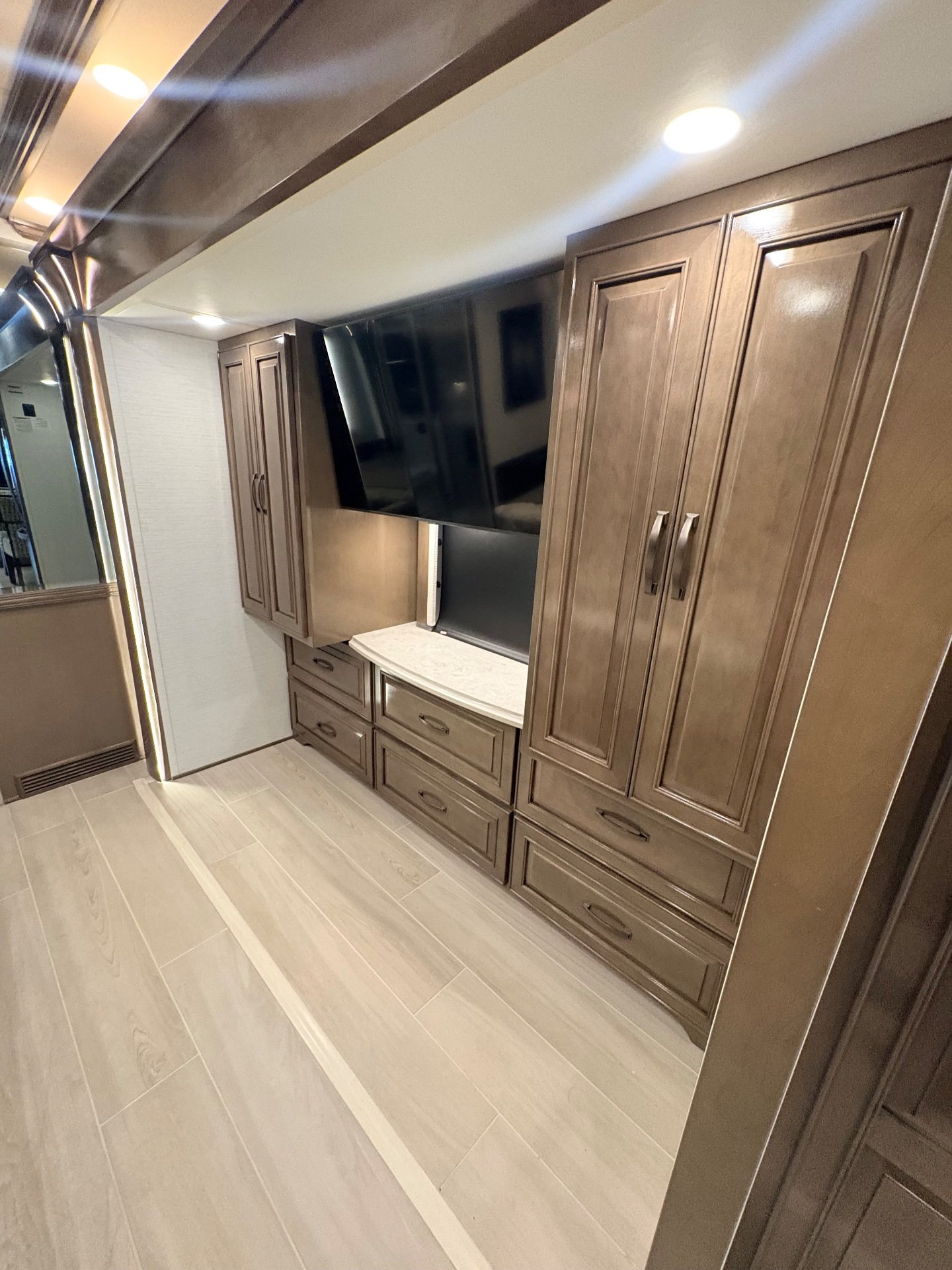 2025 Newmar Dutch Star 4369 — Bedroom wall with television, tall wardrobe cabinets, drawers, and a small countertop beside a passage