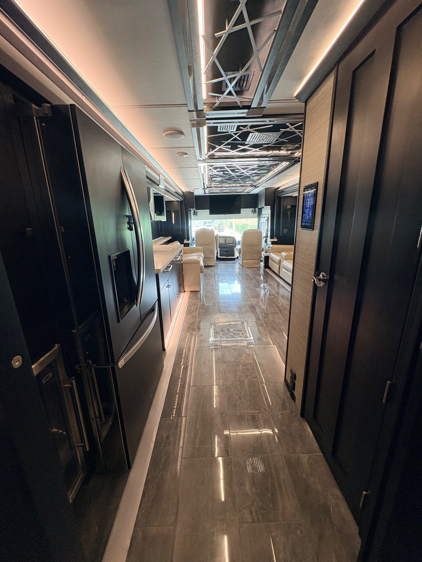 2025 Tiffin Zephyr 45 PZ — Class A motorhome overview showing refrigerator and kitchen counters, lounge seating, and front cockpit