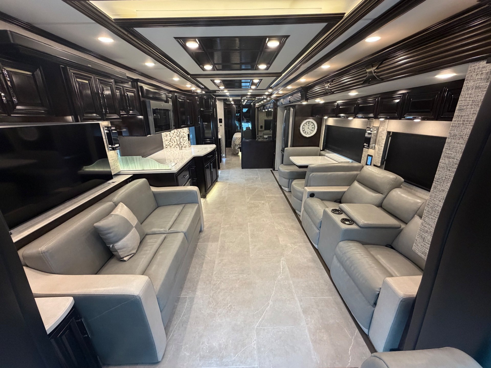 2023 Newmar Supreme Aire 4575 — Class C motorhome overview with sofas, recliners, dinette, kitchen counters, cabinetry, and open central aisle