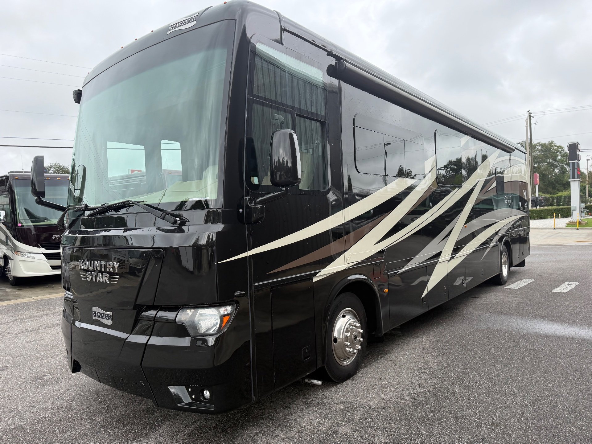 2020 Newmar Kountry Star 4037 — The front and side exterior of the motorhome with exterior graphics, wheel, windows, and awning