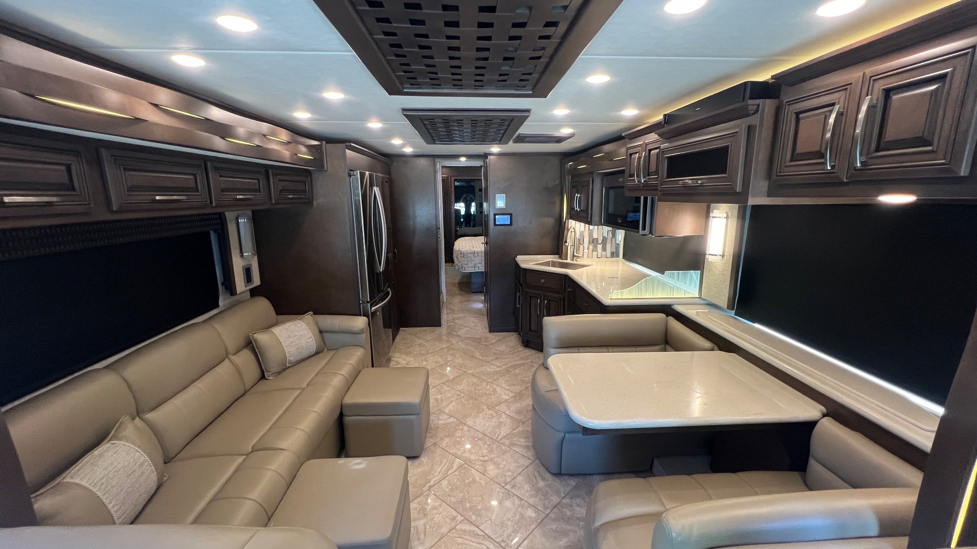 2021 Newmar New Aire 3541 — Class A motorhome living area with sofa, recliners, dinette, galley counters, refrigerator, and surrounding overhead cabinets