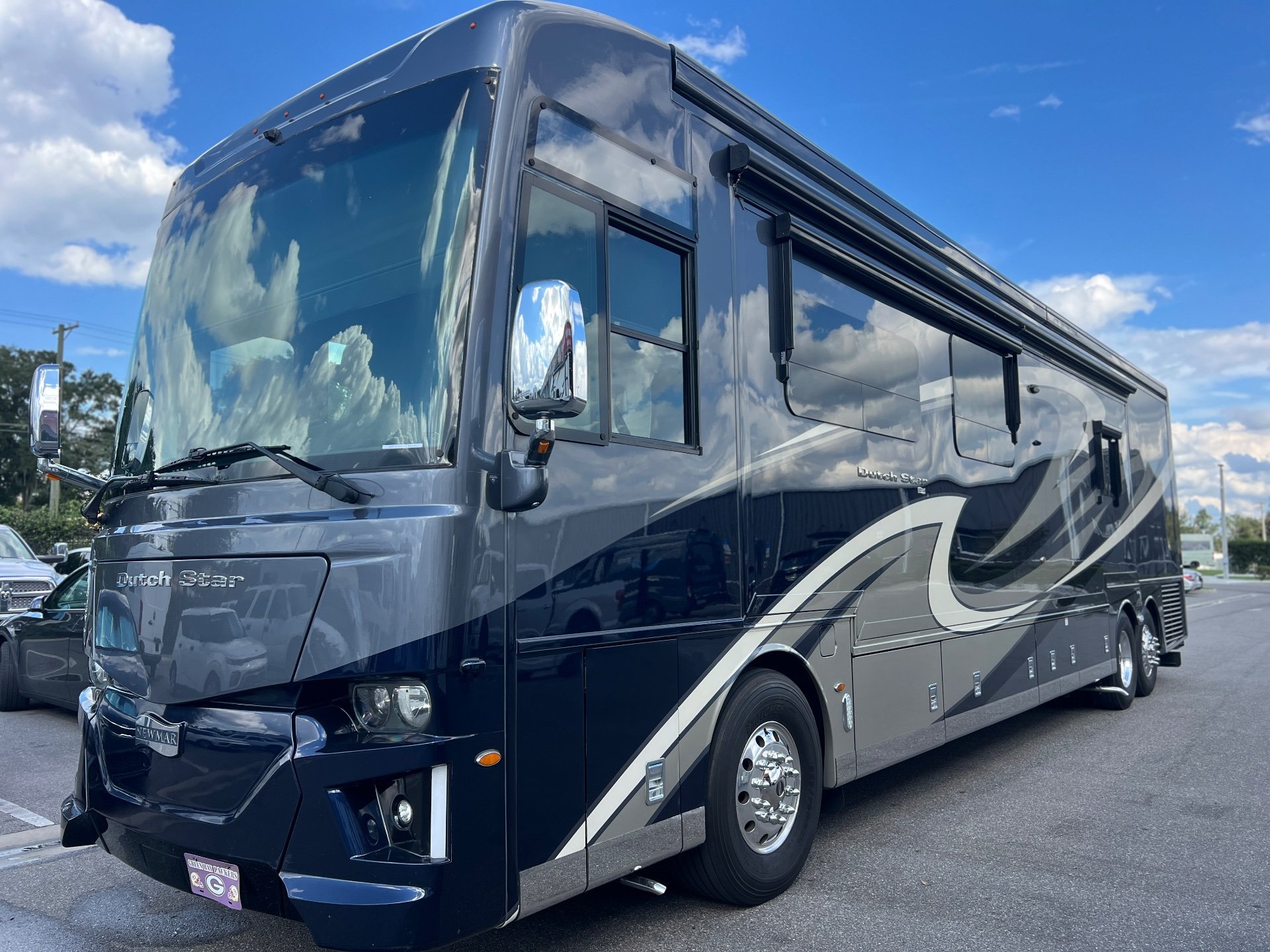 2020 Newmar Dutch Star 4328 — Exterior three-quarter photograph showing the motorhome front and opposite side, including body shell, windshield, wheels, and awnings