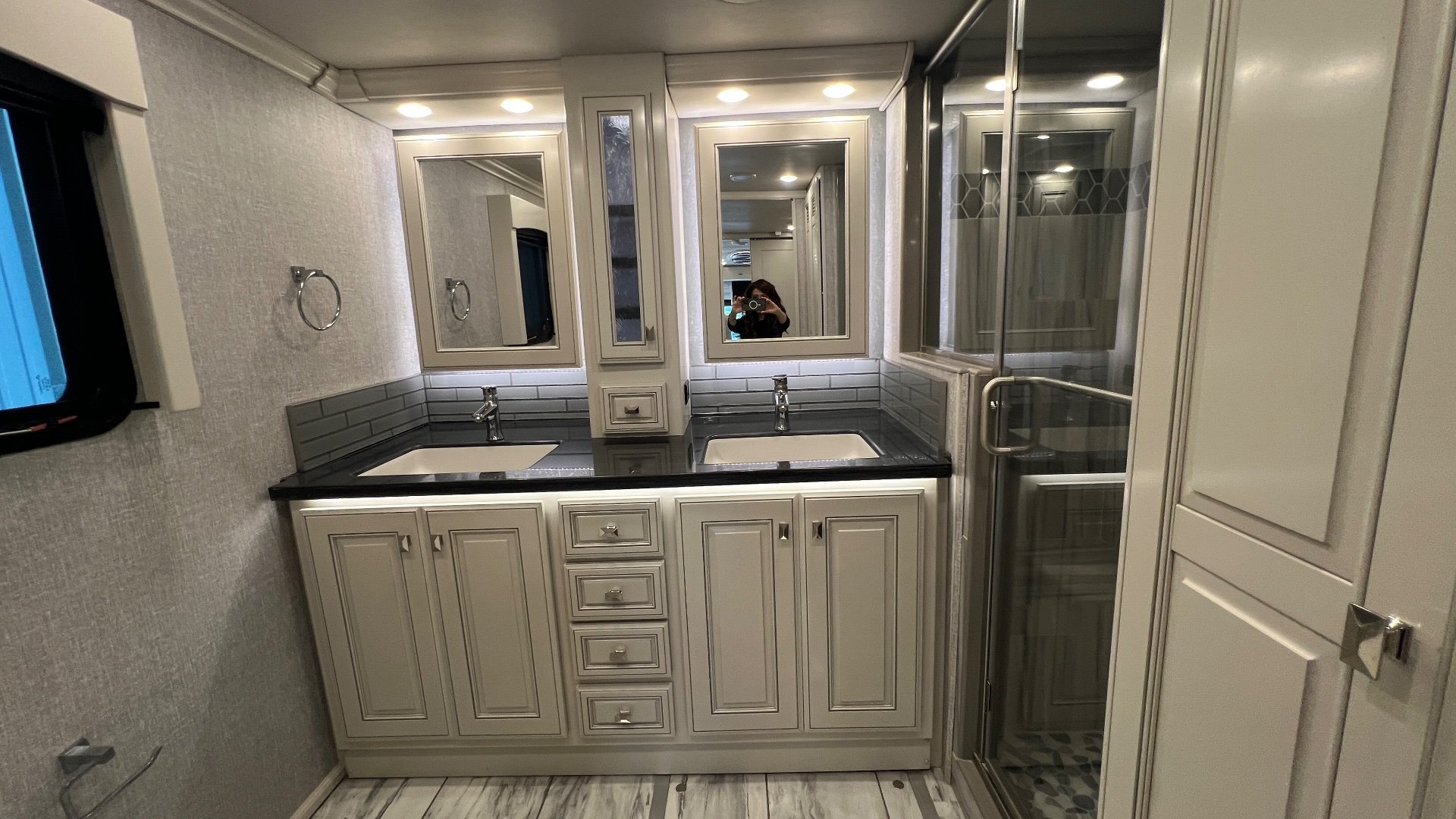 2024 Fleetwood Discovery LXE 40M — Wide bathroom view with double vanity, mirrored cabinets, glass shower enclosure, and tiled floor