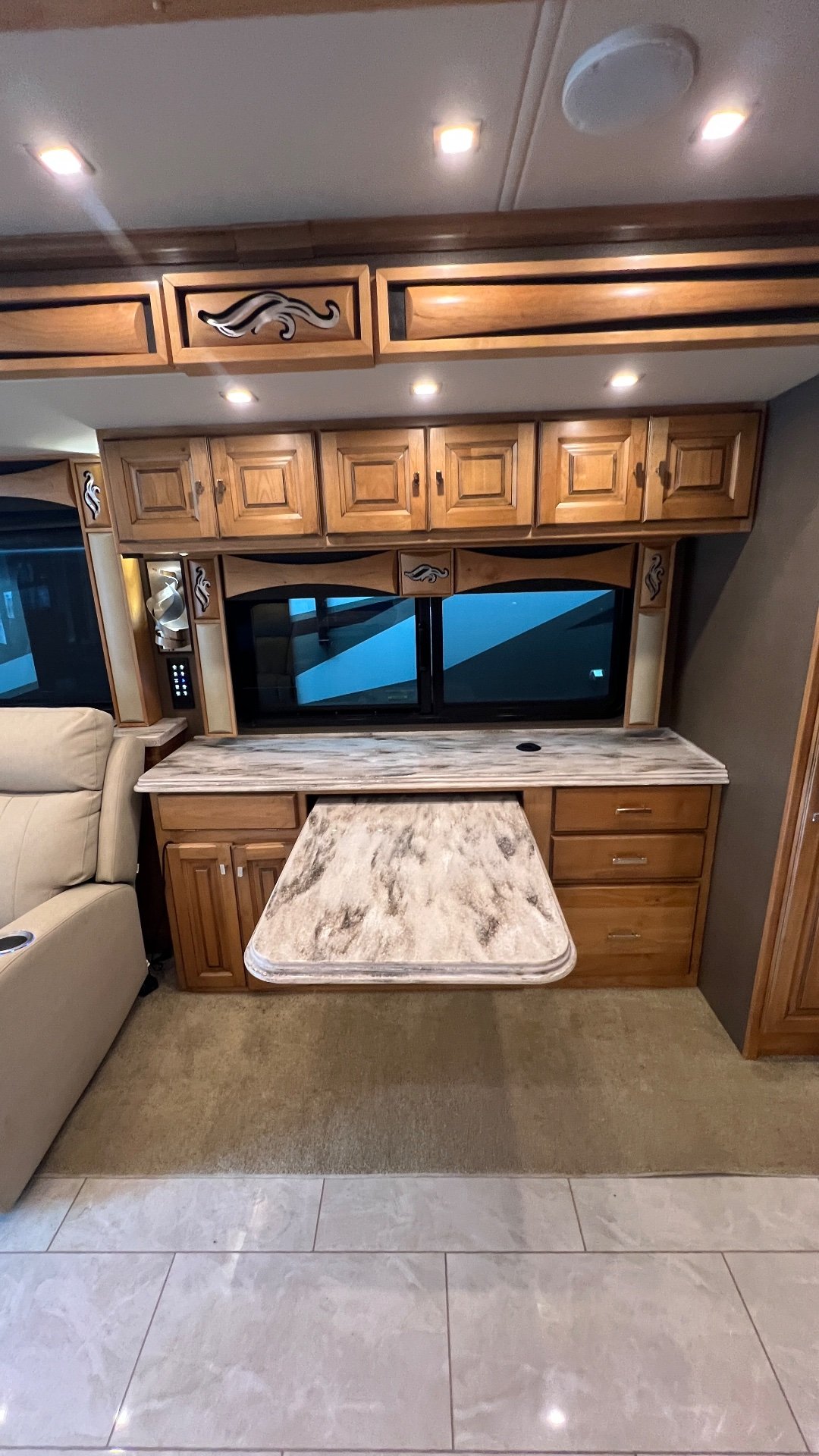 2019 Tiffin Phaeton 40 IH — Motorhome dining workstation with a retractable table, countertop, drawers, cabinets, and window
