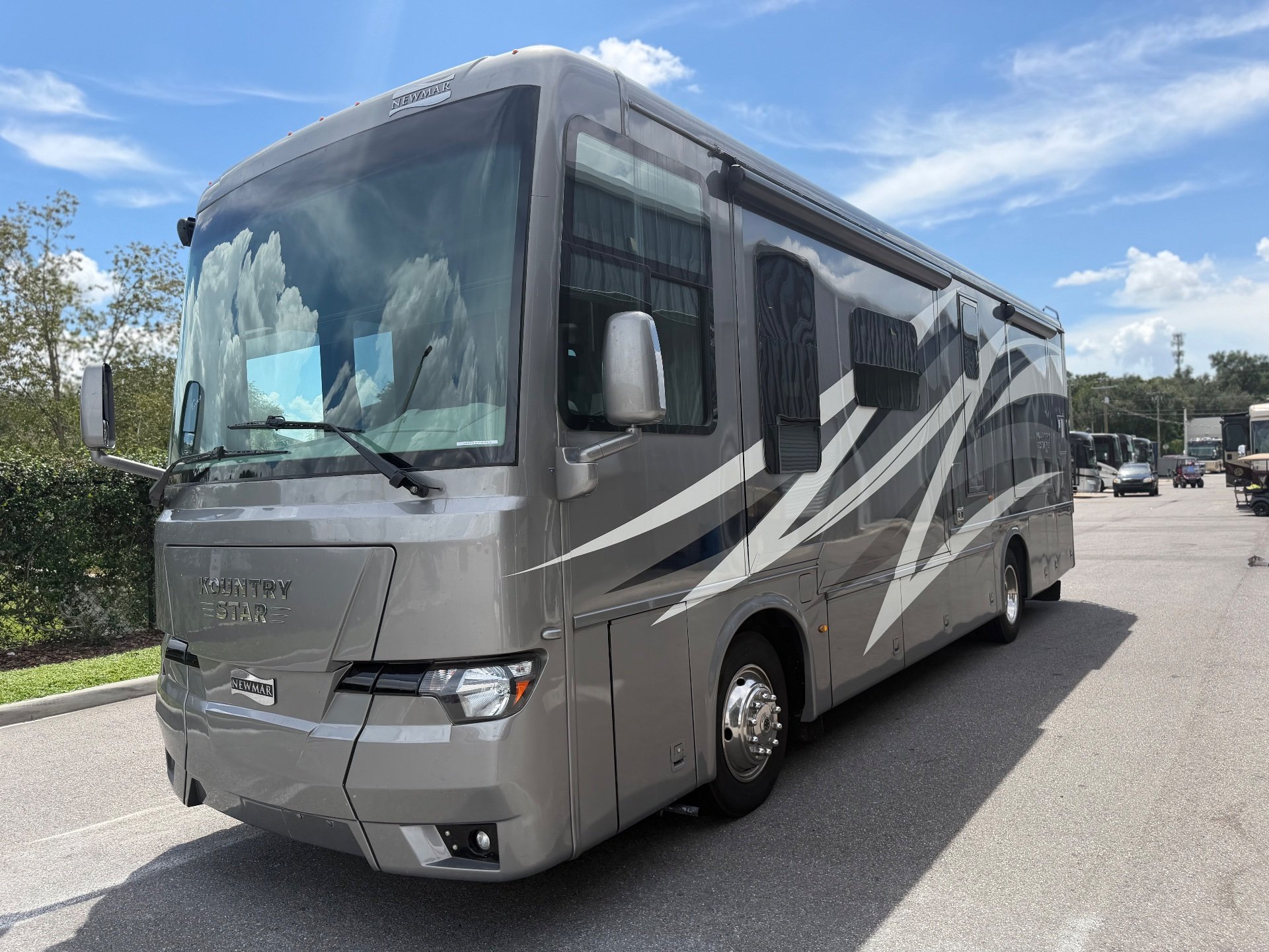 2020 Newmar Kountry Star 3412 — The motorhome's front and passenger-side exterior, including body graphics and awning