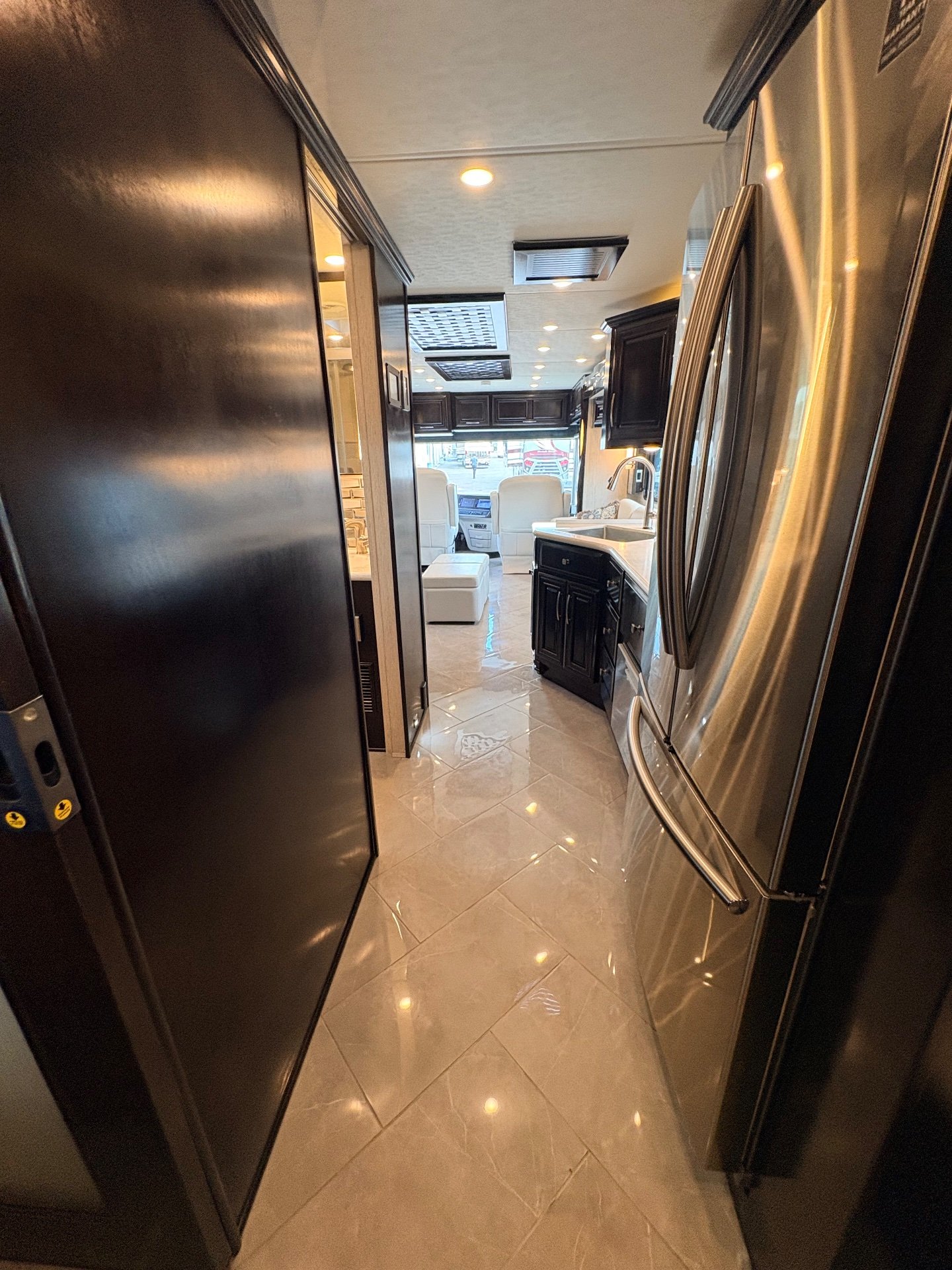 2021 Newmar New Aire 3545 — RV aisle view with refrigerator and kitchen counter in the foreground leading toward the lounge and cockpit