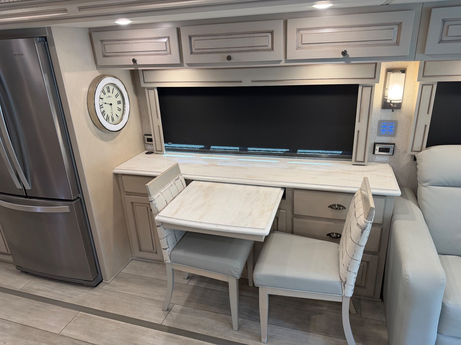 2022 Newmar Dutch Star 4369 — Two-chair dinette with expandable tabletop beside a refrigerator, lounge sofa edge, and surrounding cabinetry