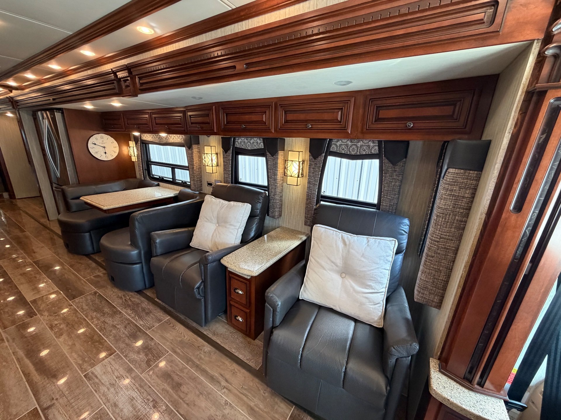 2017 Newmar Dutch Star 4369 — Leather living-area recliners and side tables face a rear dinette with booth seating, windows, and overhead cabinetry