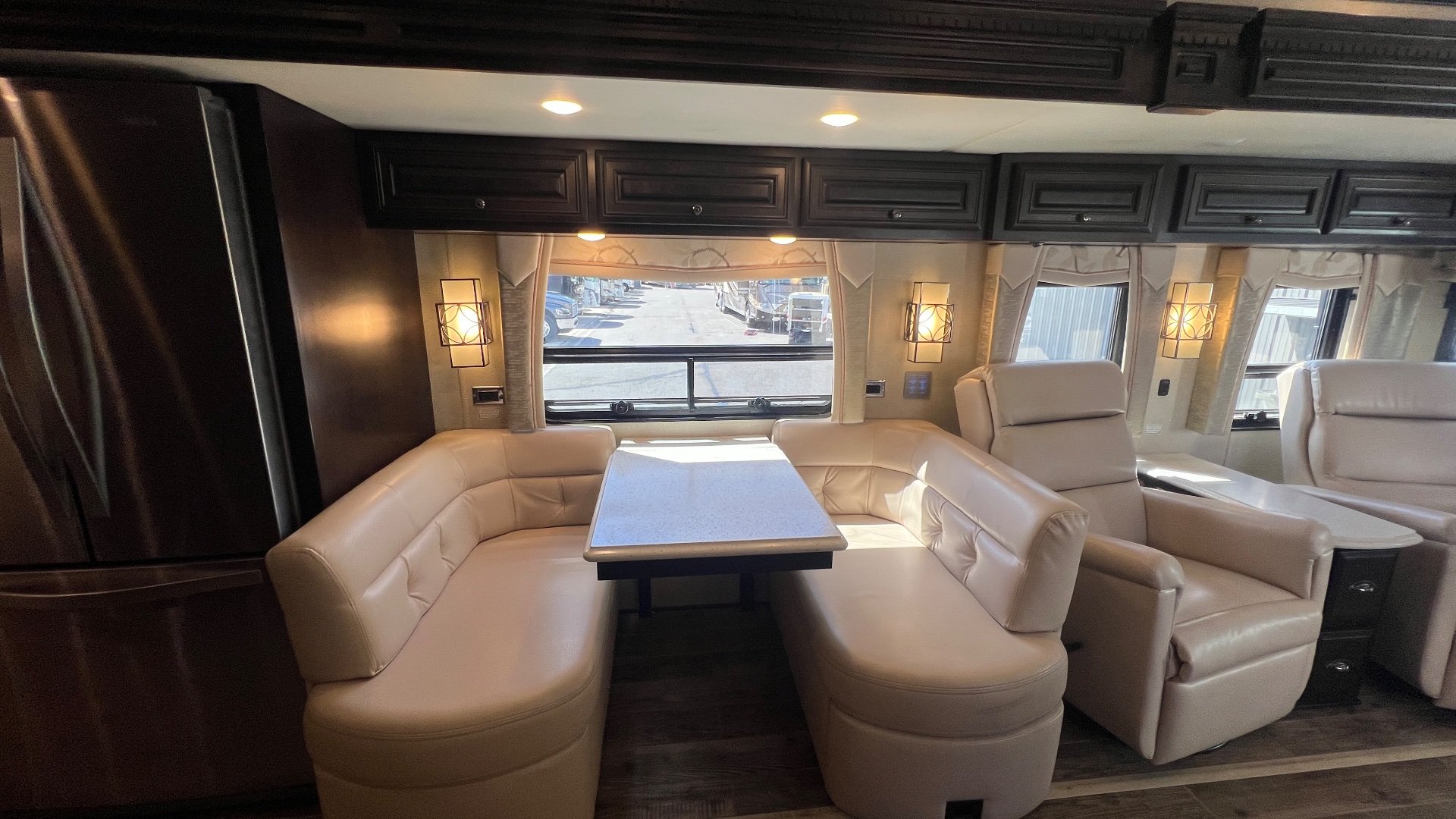 2018 Newmar Dutch Star 4369 — Dinette booth with table beside two recliners, overhead cabinets, windows, and lounge seating