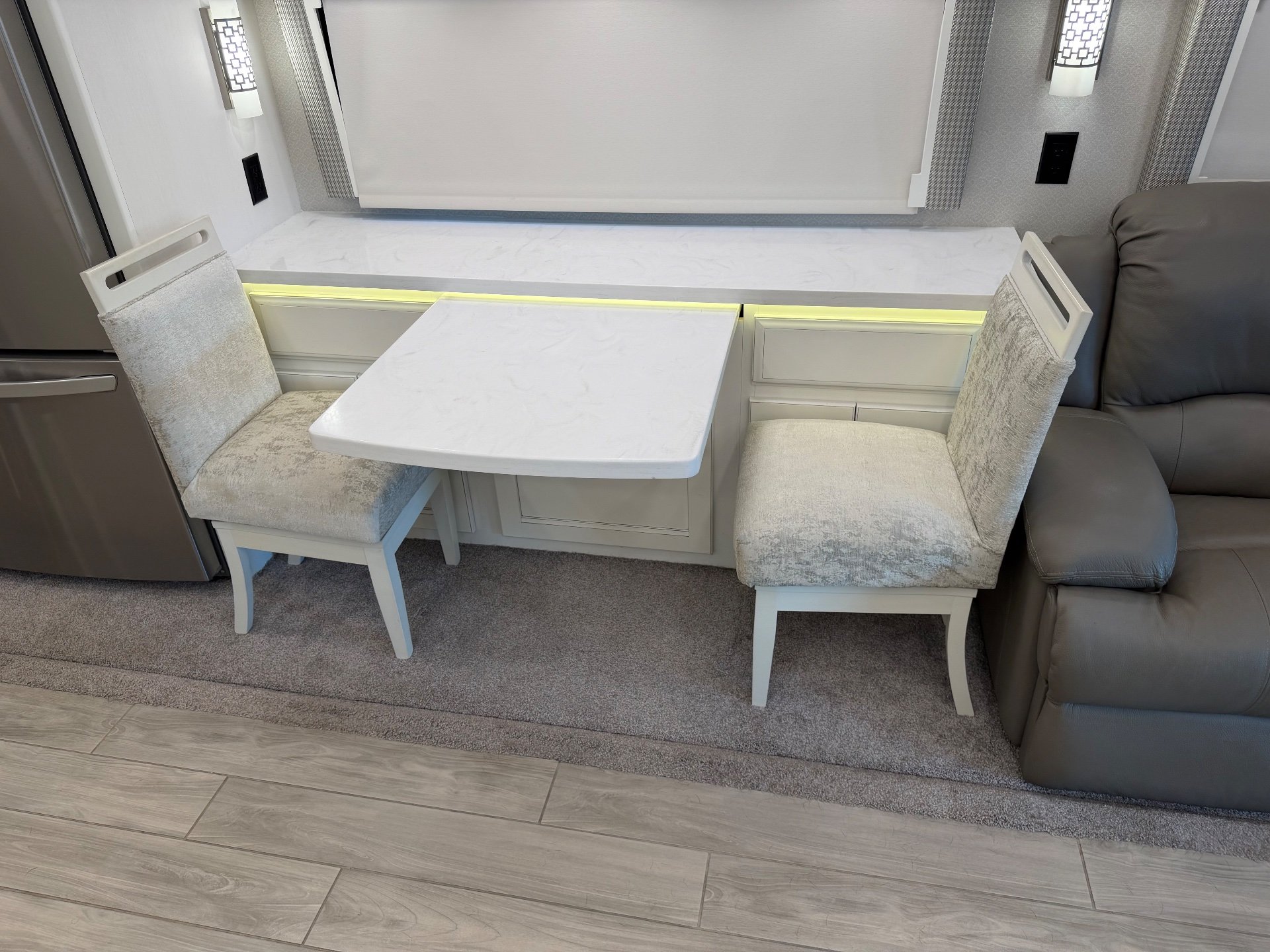 2023 Entegra Coach Aspire 40P — Motorhome dinette with two chairs beside a leather recliner, refrigerator, cabinetry, and window shades