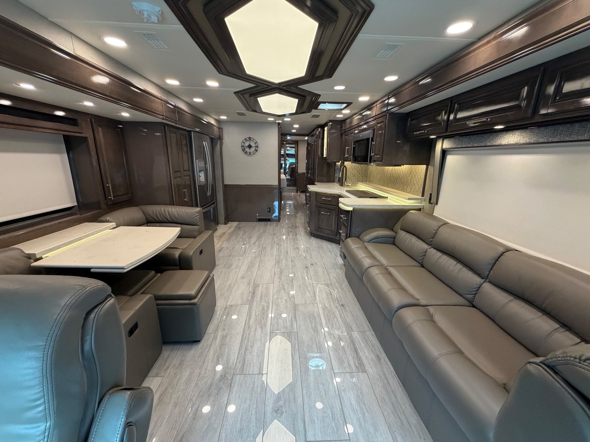 2020 Entegra Coach Aspire 44R — Class A motorhome interior with opposing leather seating, a dinette, kitchen counters, cabinetry, and a central aisle