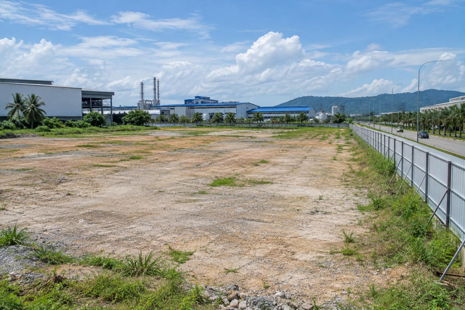Vacant cleared industrial land with factories in the background