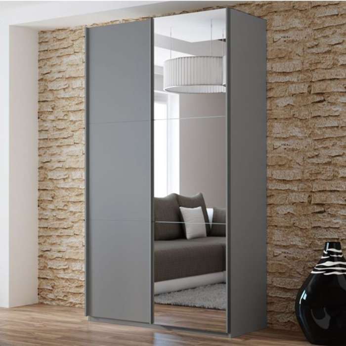 The sliding door wardrobe VIGO 120cm graphite with mirrored door in a room.