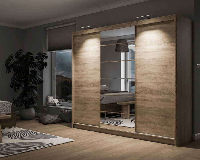 The sliding door wardrobe MALIBU oak sonoma with mirror, with LEDs in a cosy bedroom.