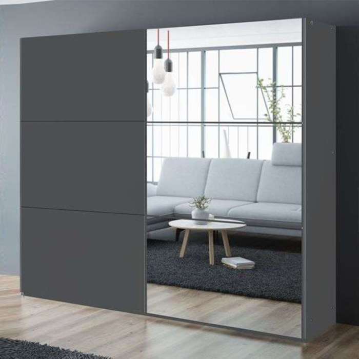 The sliding door wardrobe VIGO 250cm graphite with mirrored door in a room.