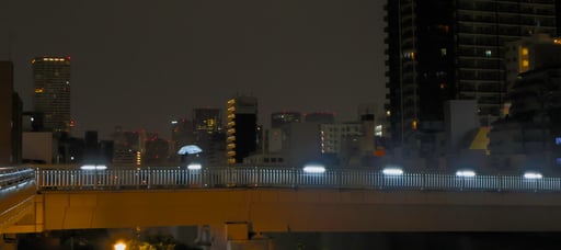 a couple crosses a long bridge late at night in osaka