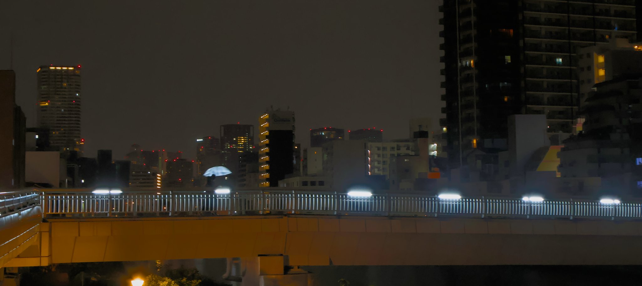 a couple crosses a long bridge late at night in osaka