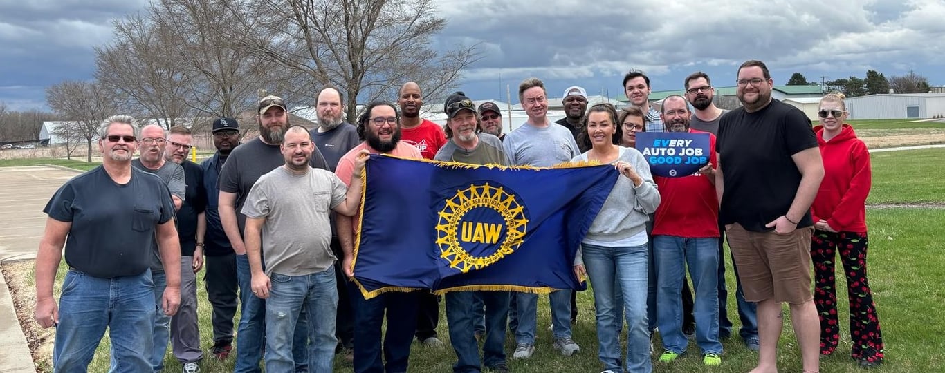 Image of Stand Up Sit Down Committee members smiling and holding a UAW flag