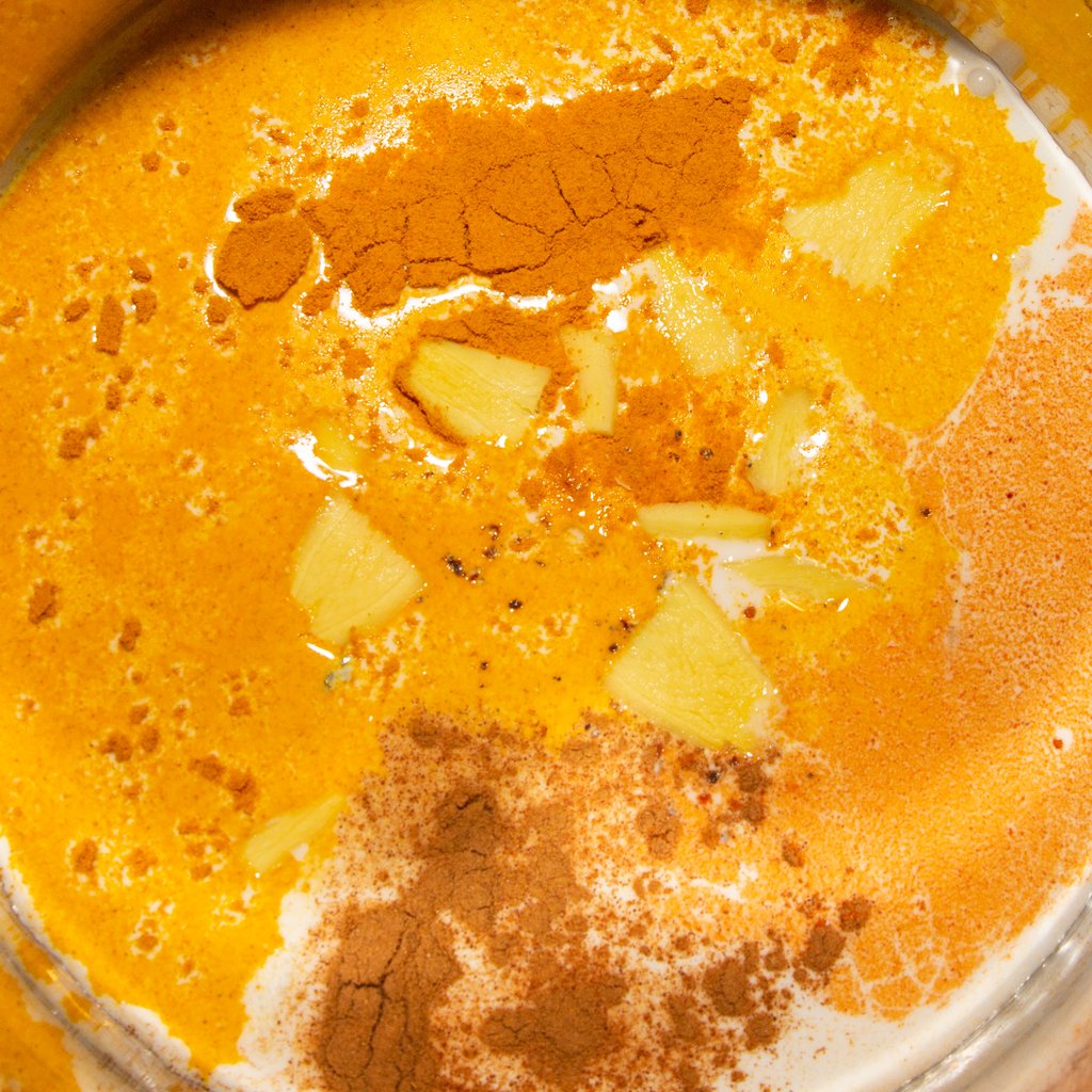 Leche de coco con las especias y las rodajas de jengibre como preparación para la mezcla de helado de leche dorada.
