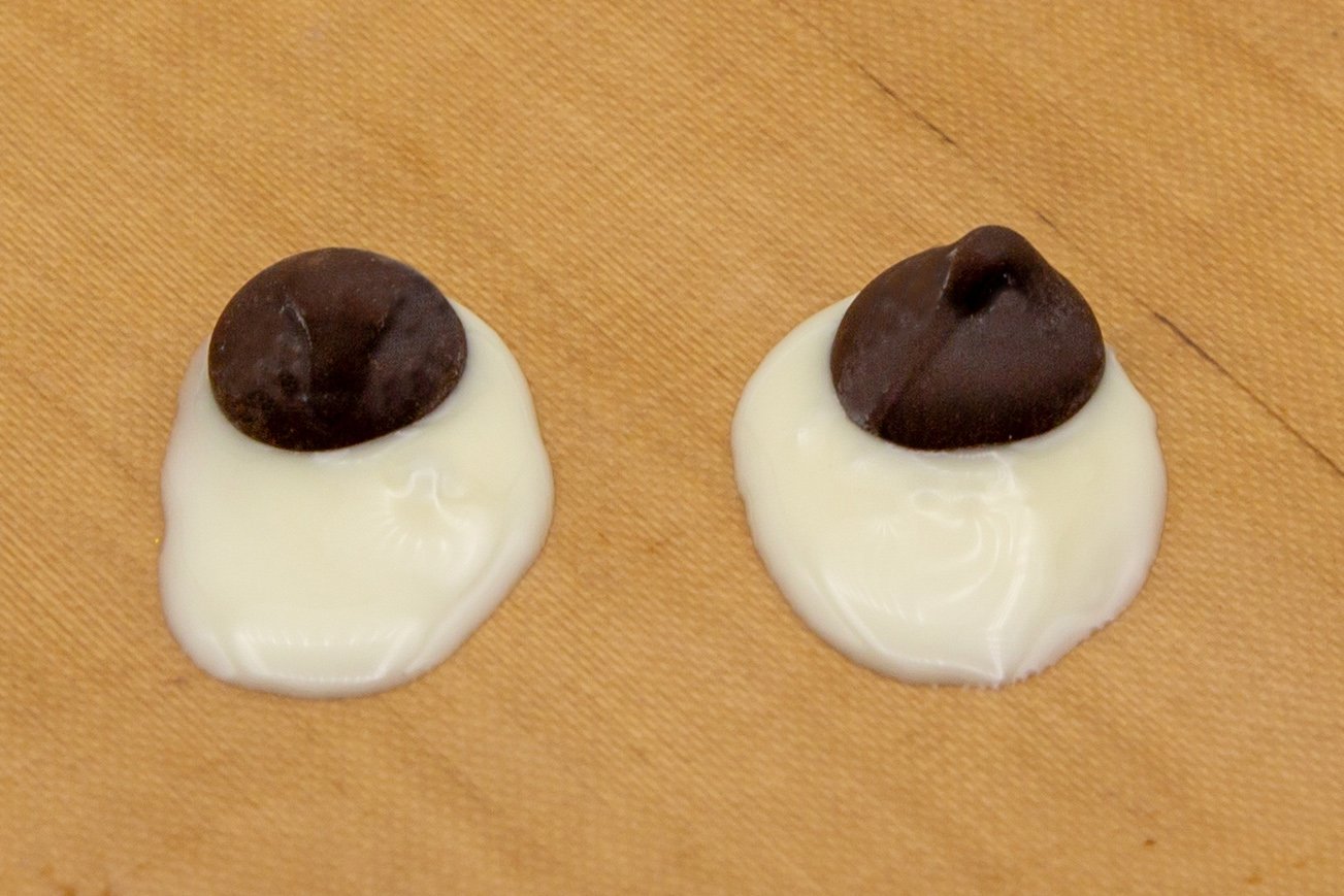 Para los ojos, haz un óvalo en papel de horno con chocolate blanco y pon dentro una gota de chocolate negro.
