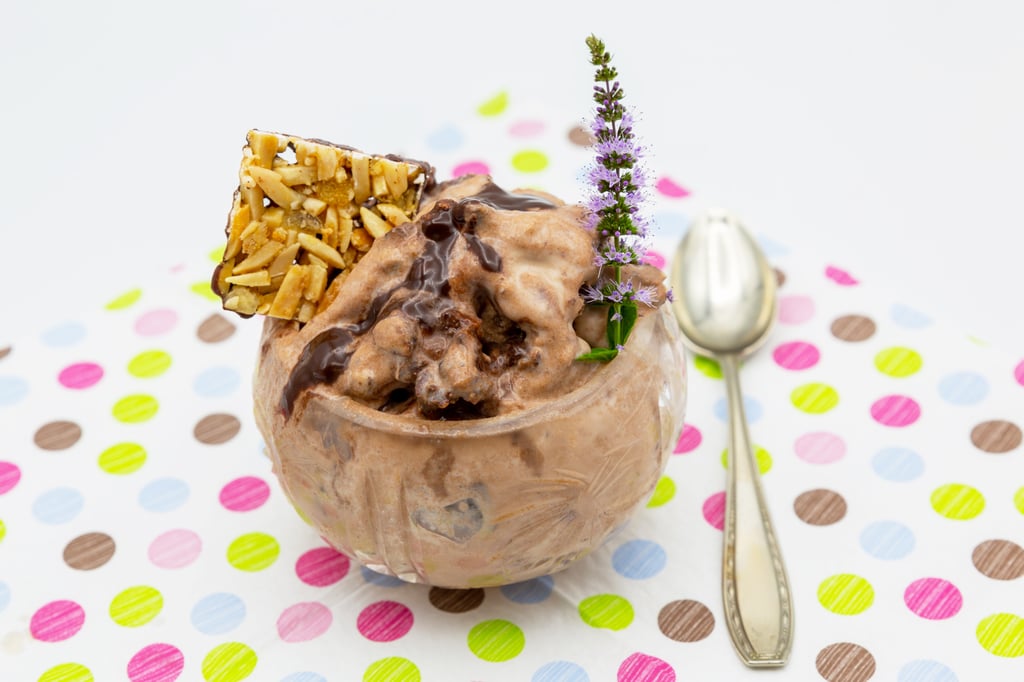 Cremiges Nougat-Eis serviert mit Schokoladen-Sauce und Nussplättchen.