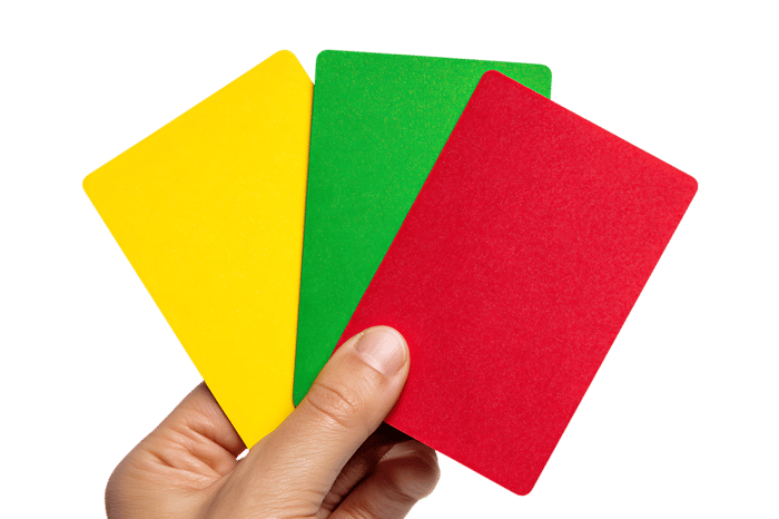 Hand holding yellow, green, and red cards.