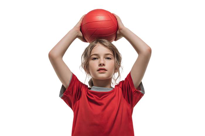 Young athlete holding a red ball above head.