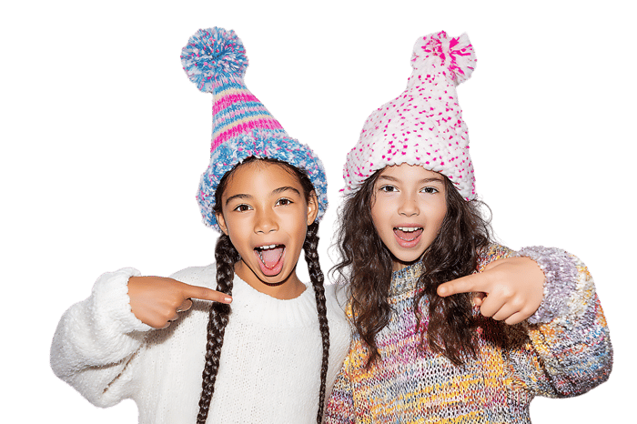 Two girls in winter hats point playfully.
