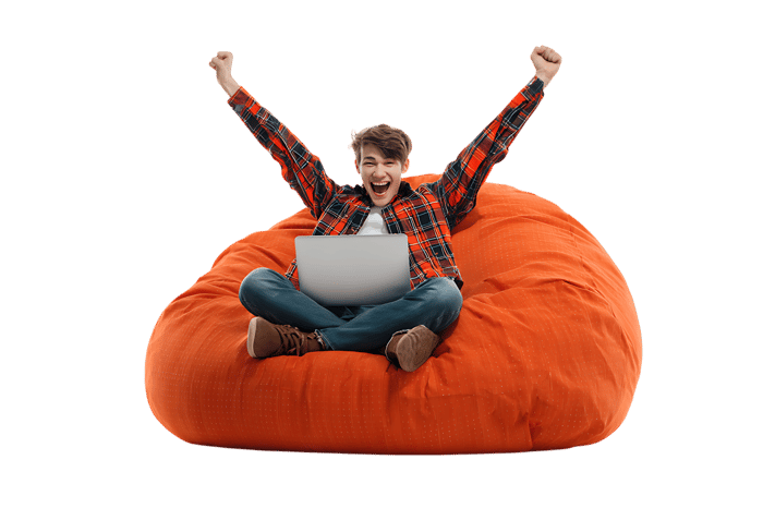 Excited young man using laptop on orange beanbag chair