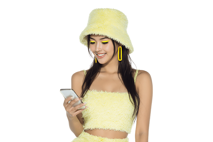 Smiling woman in yellow bucket hat using smartphone.