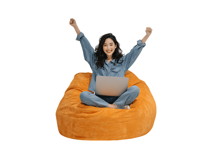 Joyful young woman celebrating success while working from home on a comfy beanbag chair.