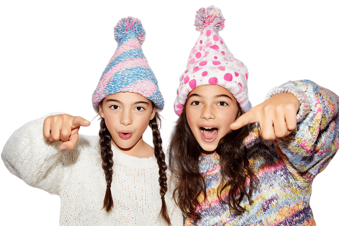 Two girls point playfully, winter hats on.