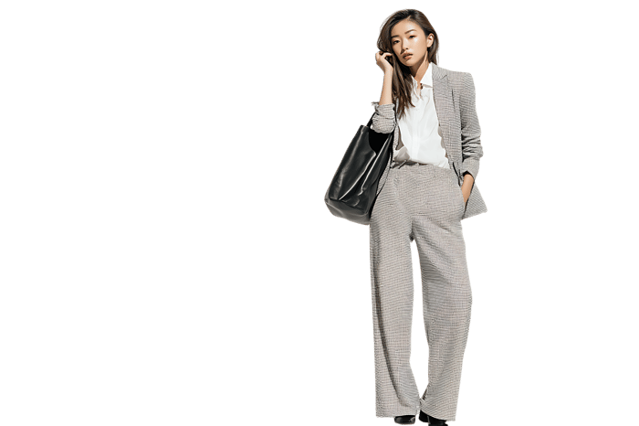 Professional female model in a modern grey pantsuit and tote bag.