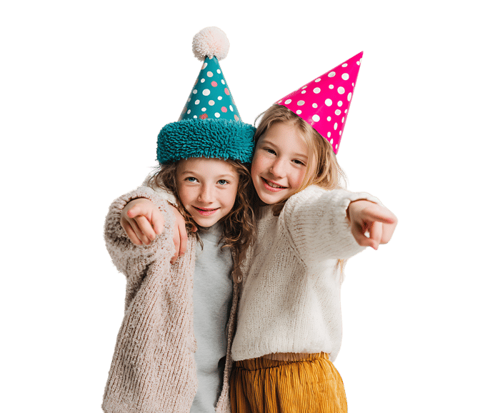 Two girls in party hats point playfully.