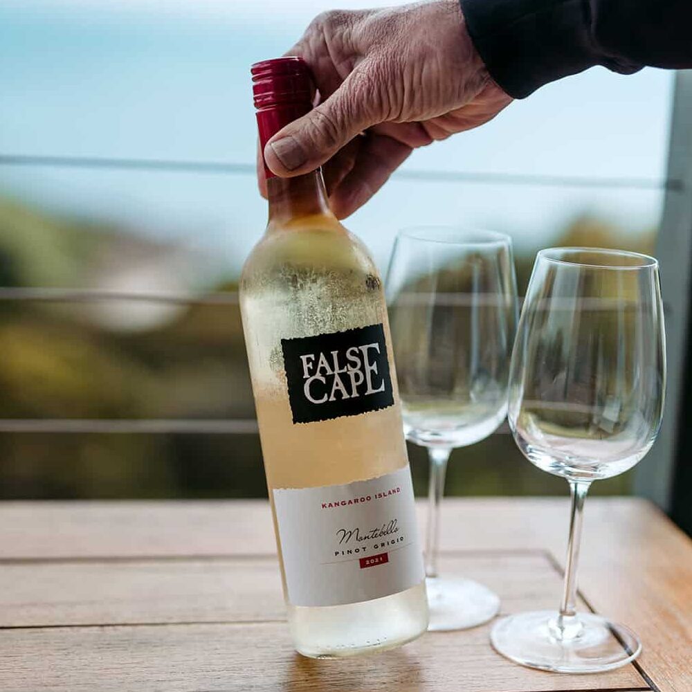 Local South Australian wine bottle and two glasses with ocean behind it
