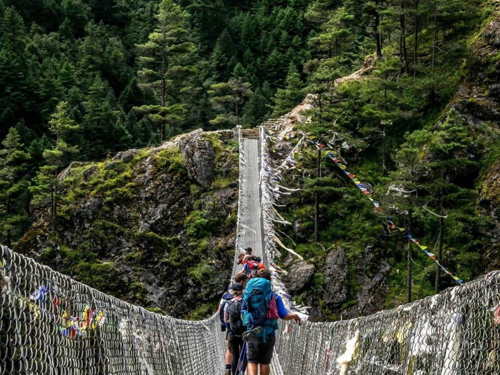 Trekkers walking across a long suspension bridge