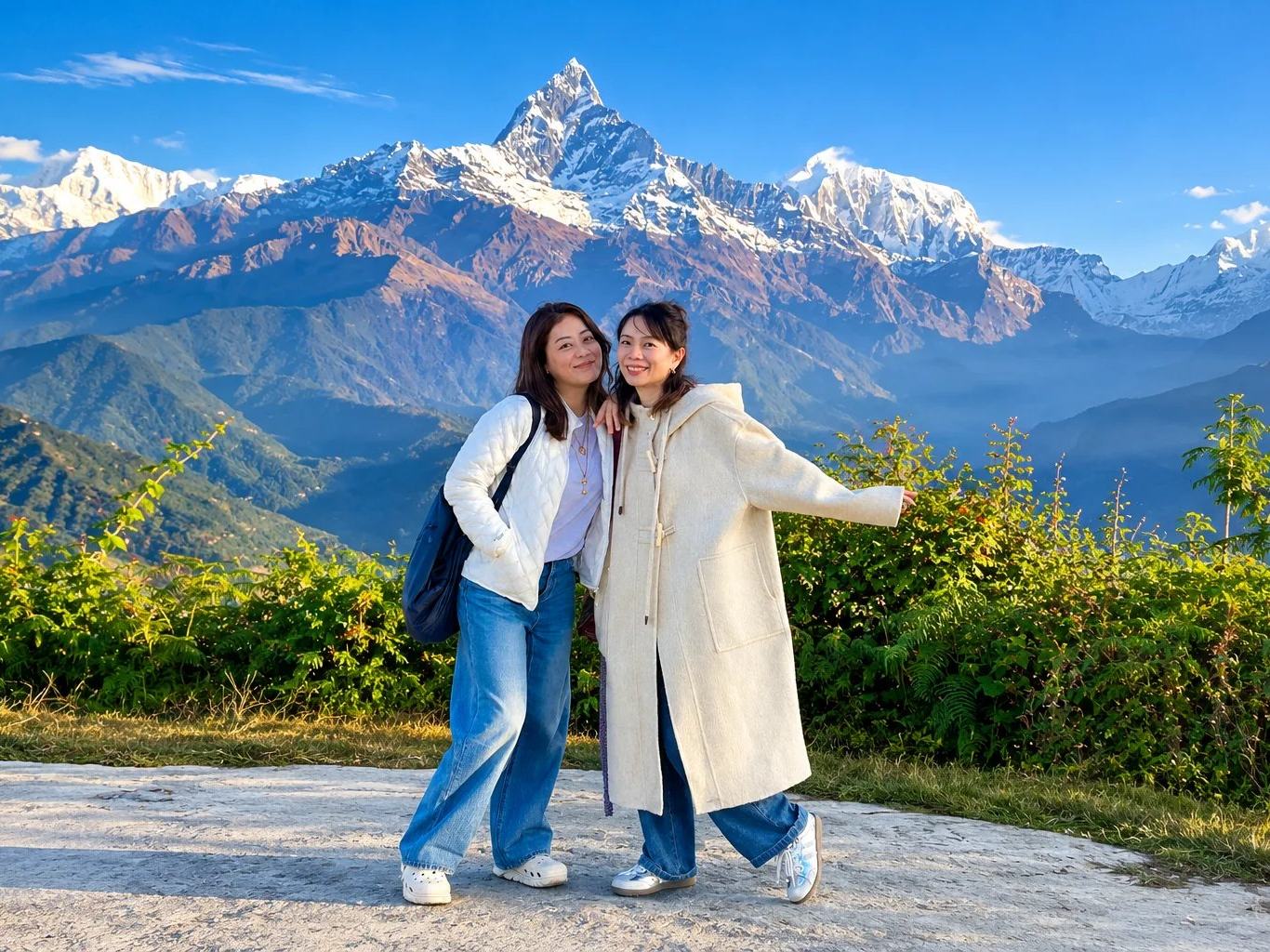 Two travellers at a hillside viewpoint below Machhapuchhre and the Annapurna range near Pokhara, Nepal