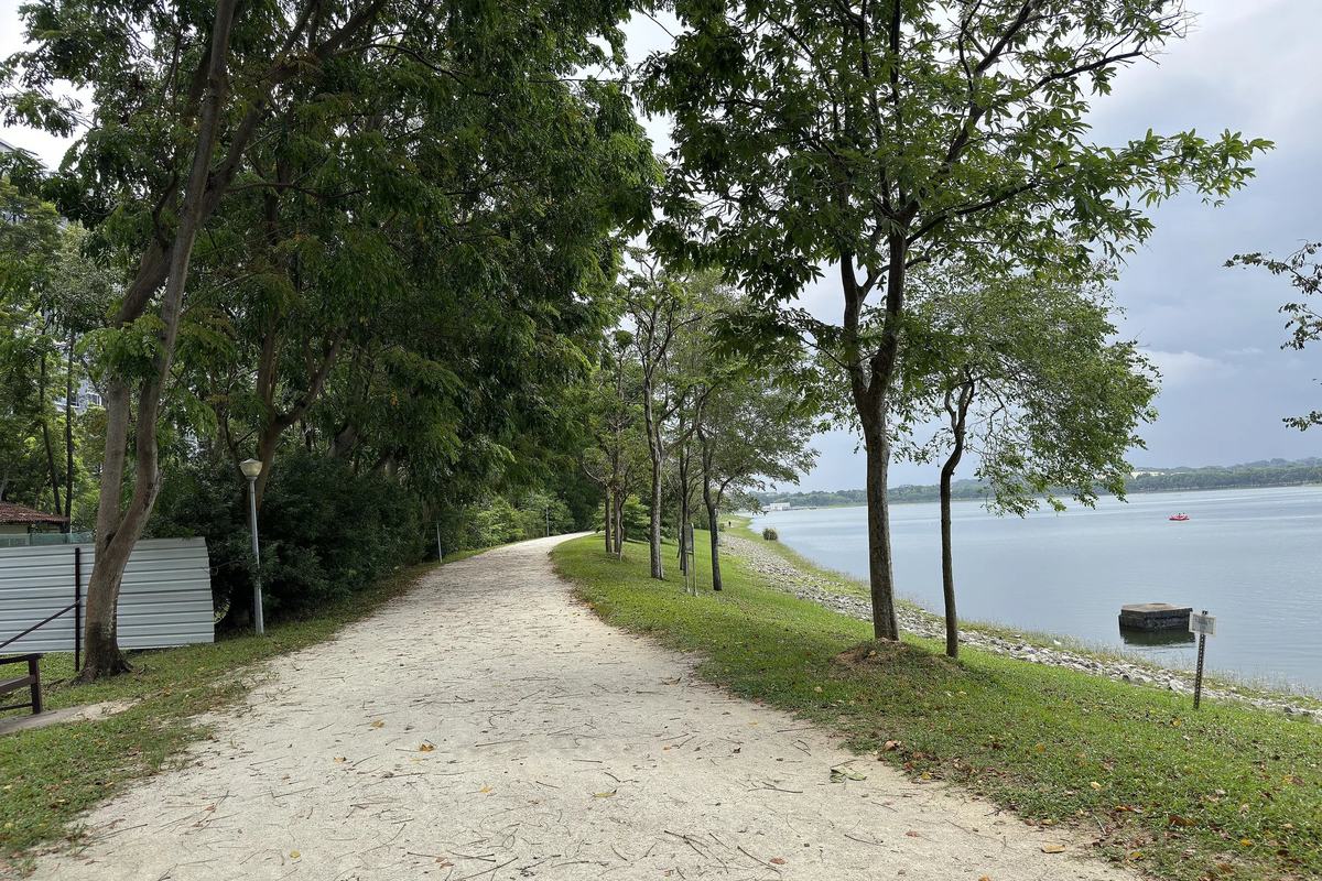 A tree-lined gravel path along the shore of Bedok Reservoir, Singapore