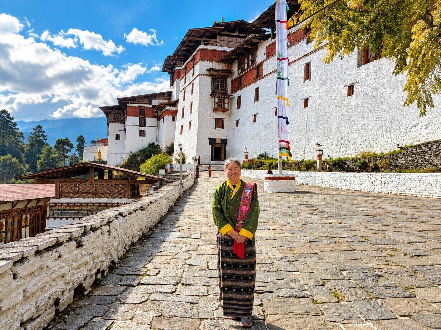A traveller in a Bhutanese kira on the stone path to a dzong