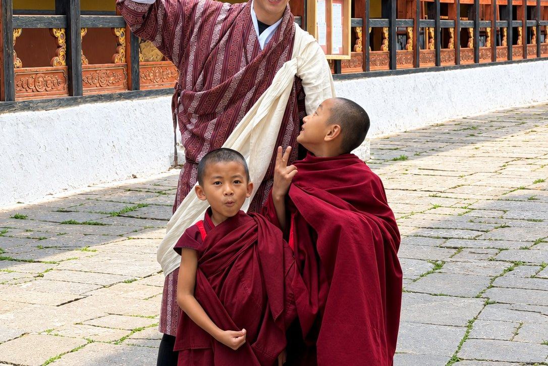 A guide in a gho with young novice monks in the courtyard