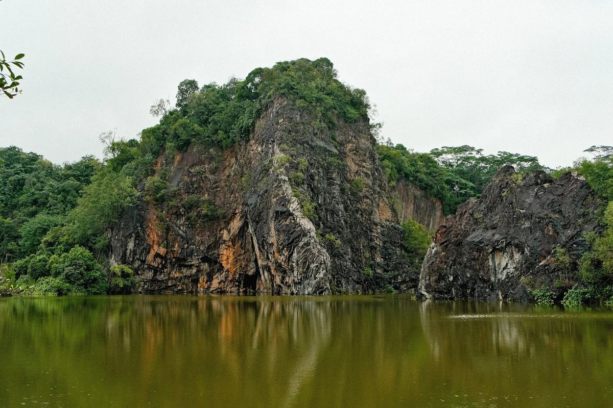A sheer granite quarry cliff reflected in the lake at Bukit Batok, Singapore