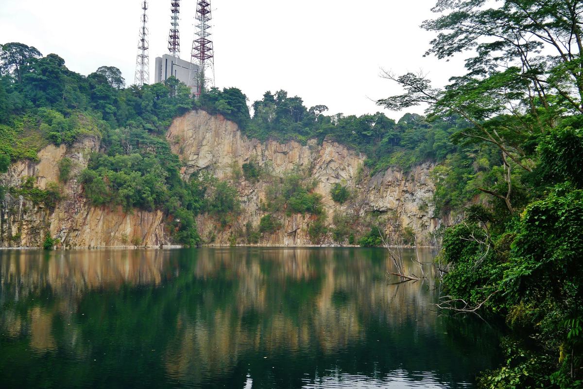 A flooded quarry below Bukit Timah Hill, its rock face reflected in still water, Singapore